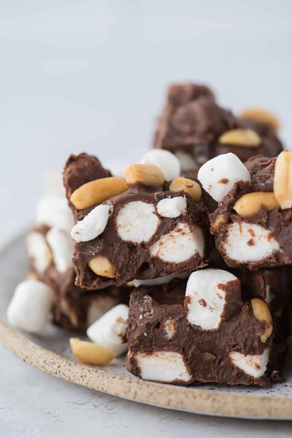 rocky road fudge cut into squares on a white speckle plate with a white background