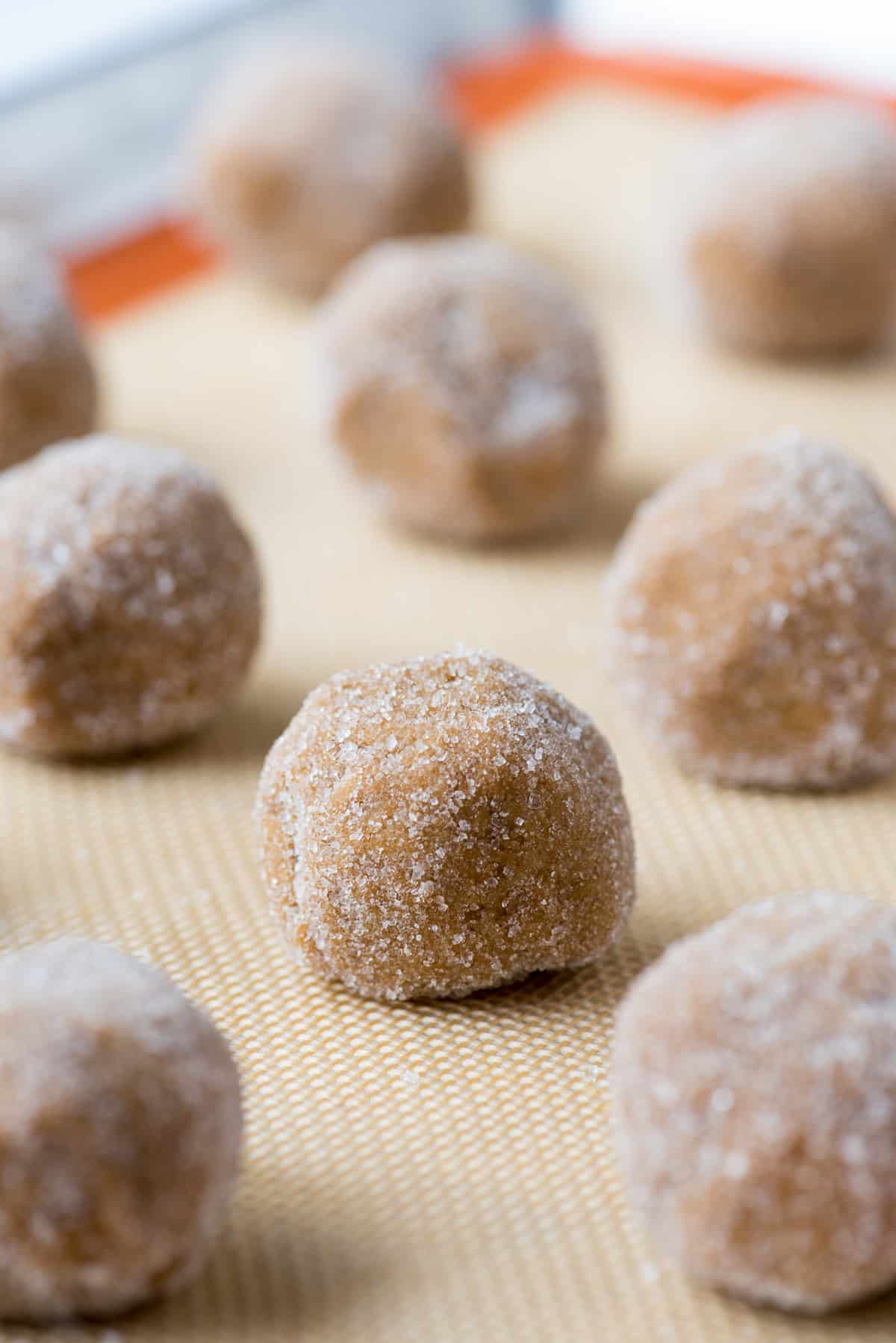 molasses ginger cookie dough balls rolled in sugar on silicone baking mat