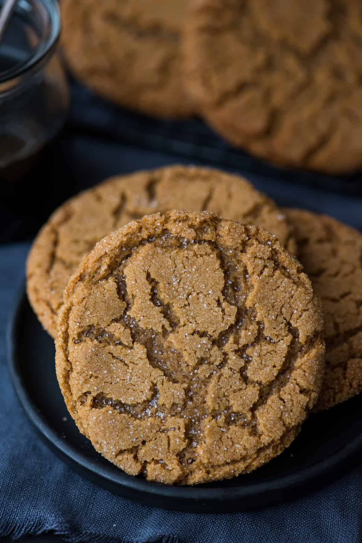 molasses cookies on dark plate on dark background with molasses in the background