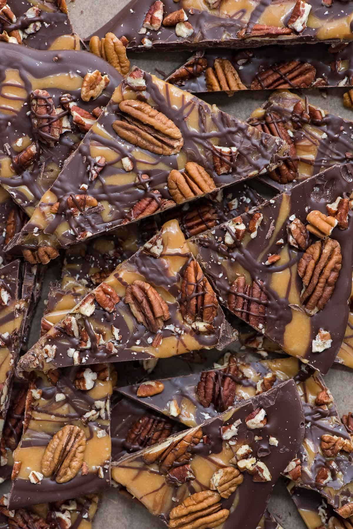 turtle bark with chocolate, caramel and pecans broken into pieces on brown parchment paper