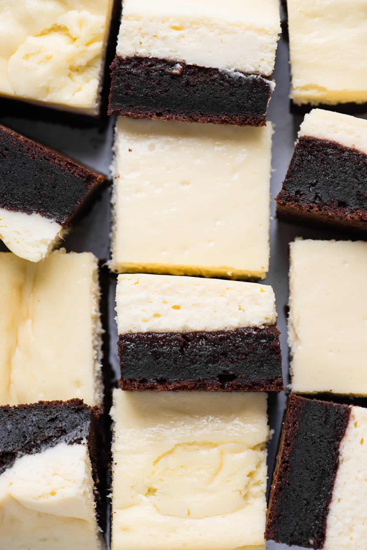 cheesecake brownies cut into squares and arranged randomly on white background