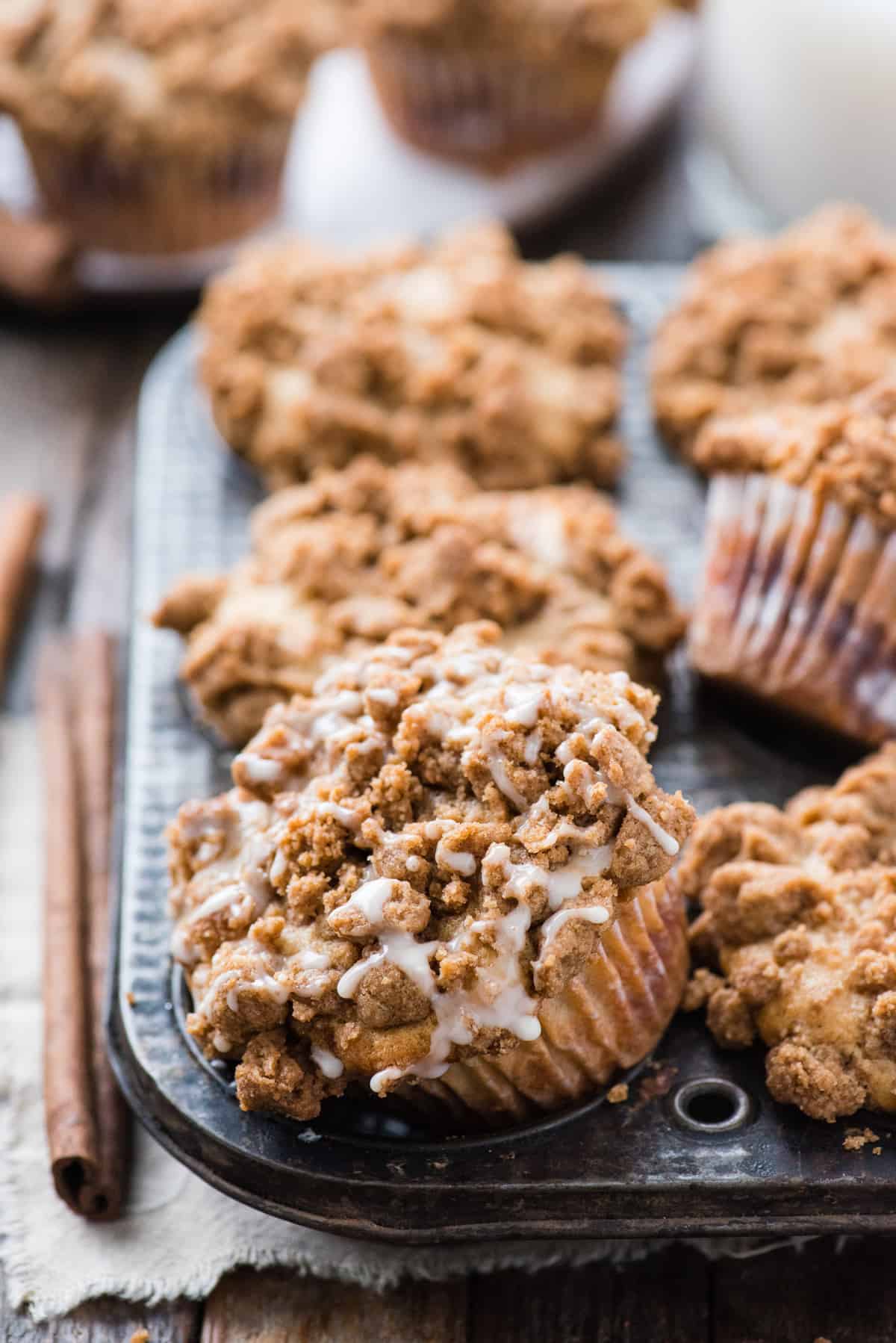 six coffee cake muffins in metal muffin pan on wood background