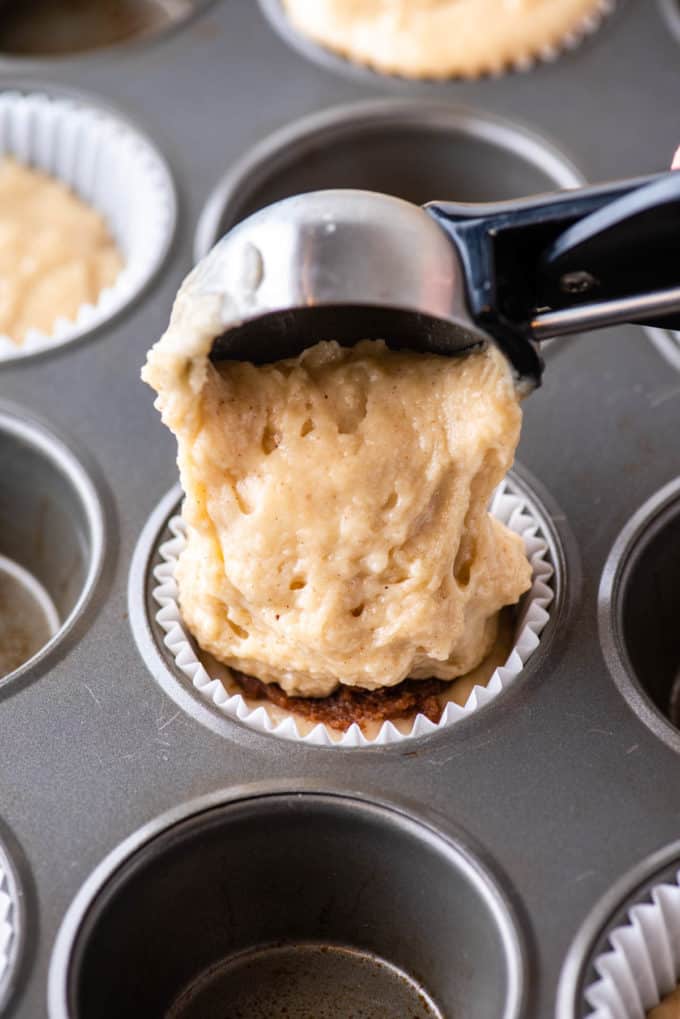 adding a scoop of batter to a muffin pan