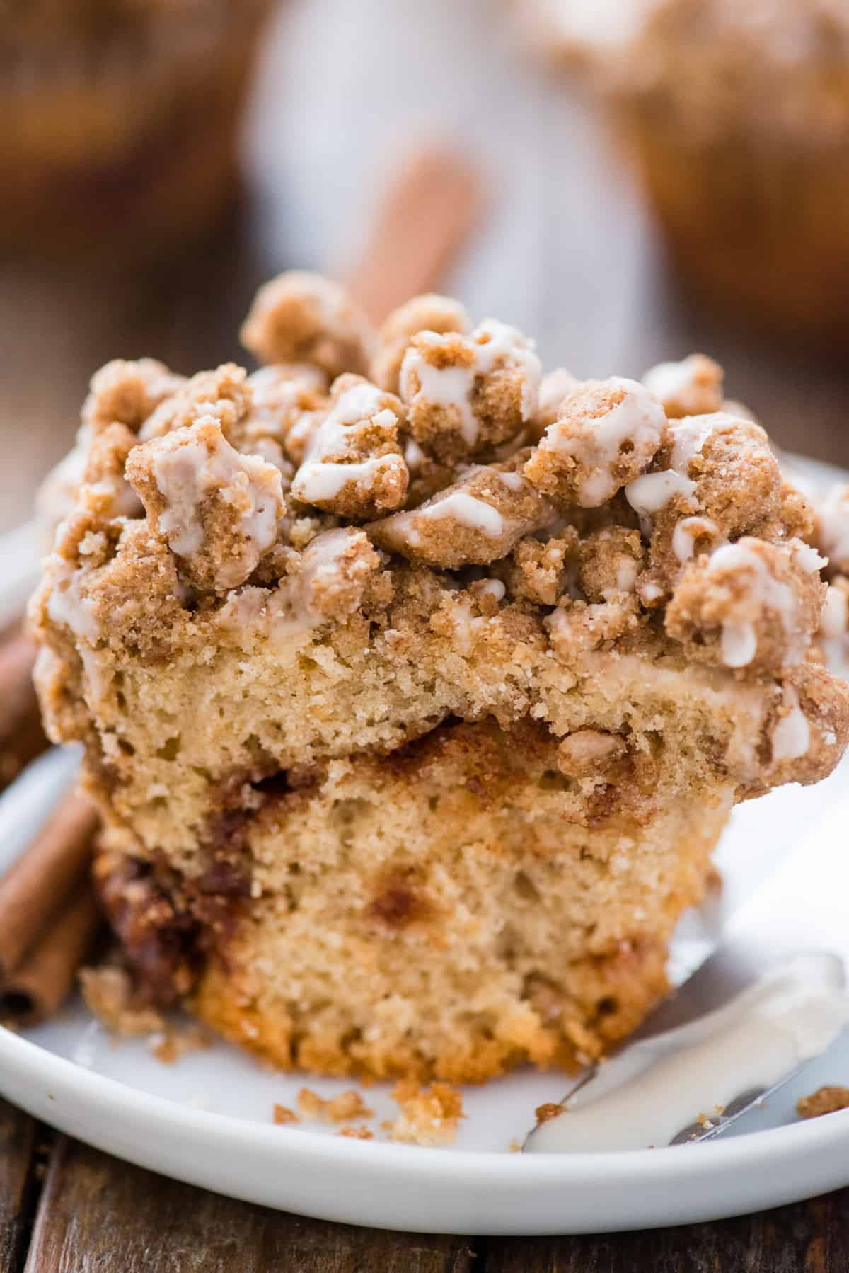 coffee cake muffin cut in half with a ribbon of cinnamon sugar baked in with crumb topping on white plate 