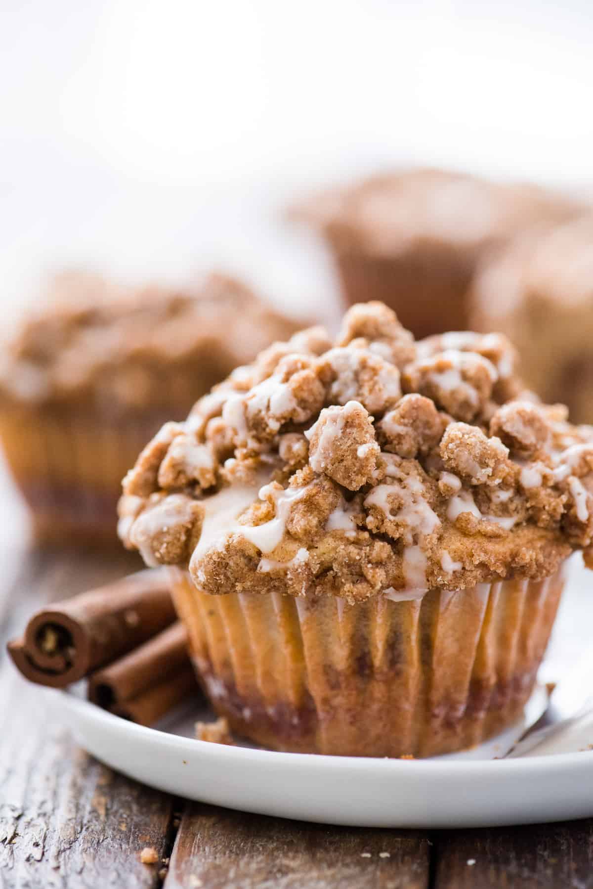 coffee cake muffin with crumb topping on white plate on wood background