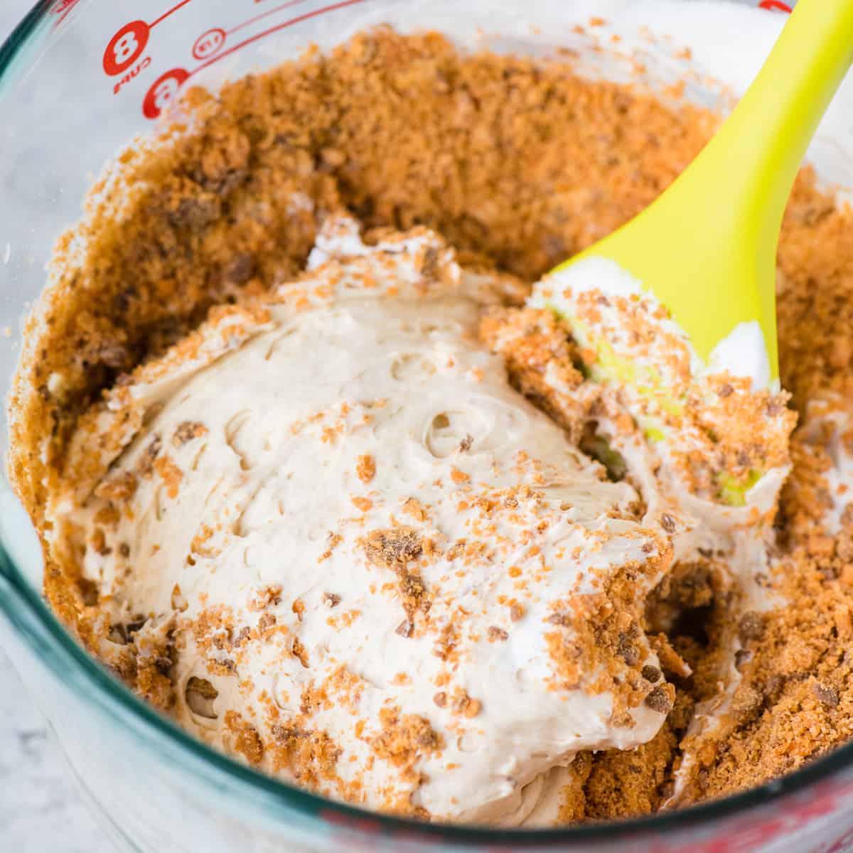 creamy butterfinger pie filling in glass bowl with spatula