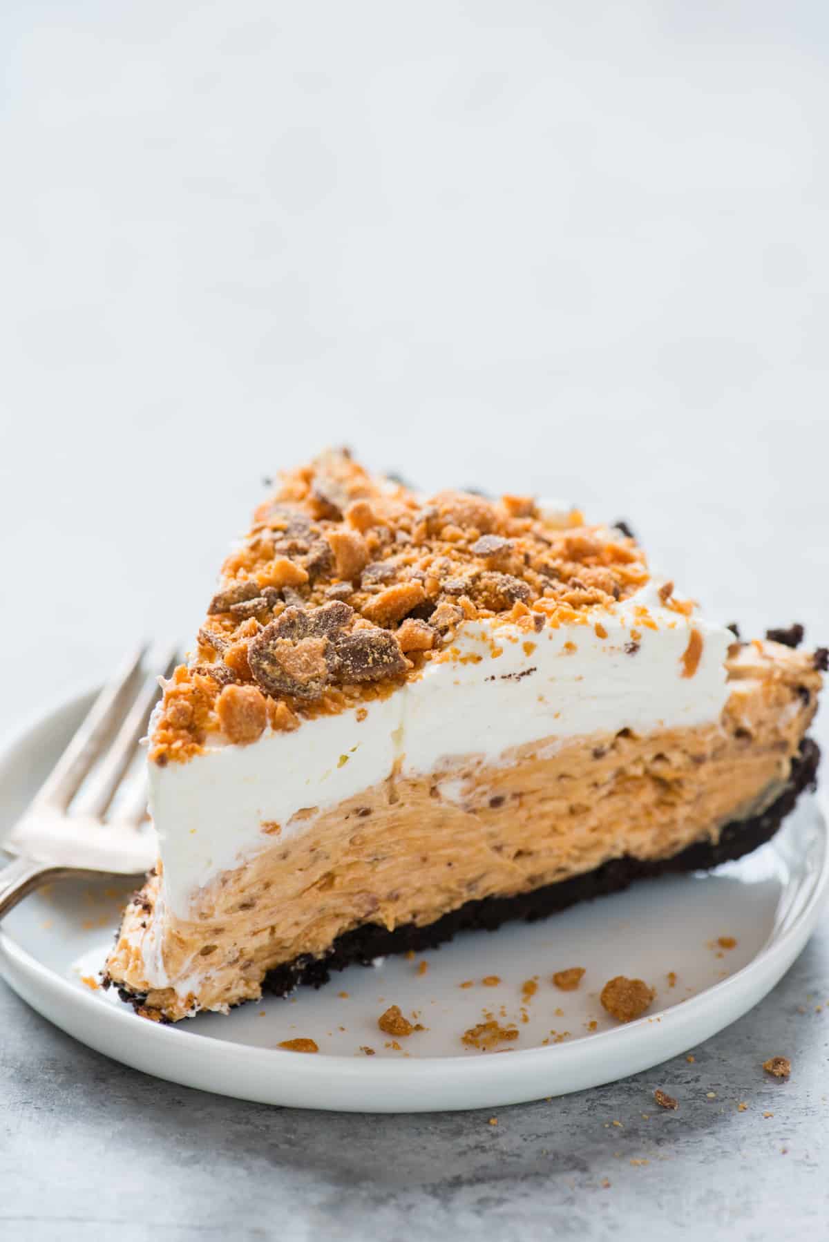 slice of butterfinger pie on white plate on gray background