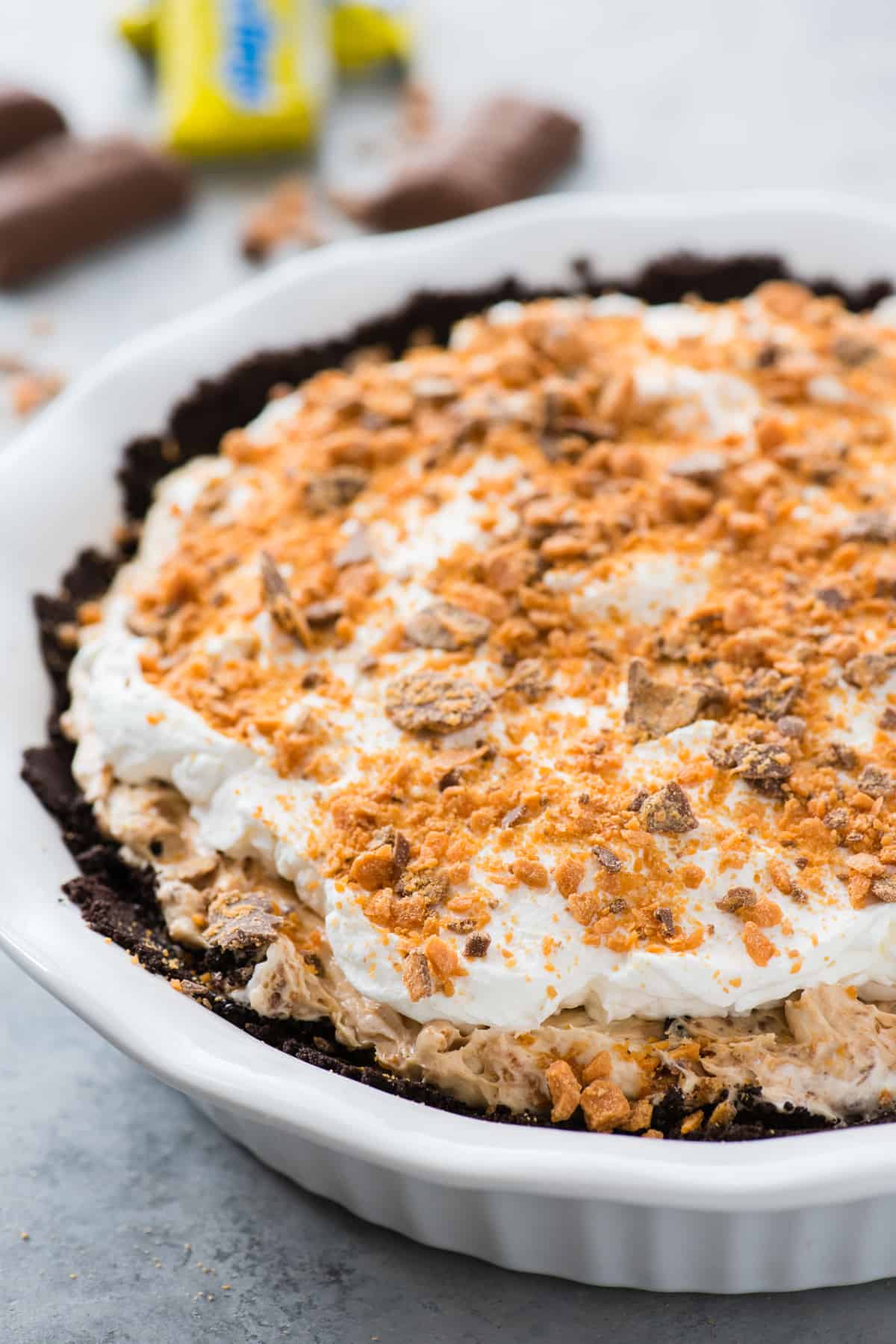 whole butterfinger pie in white pie pan on gray background
