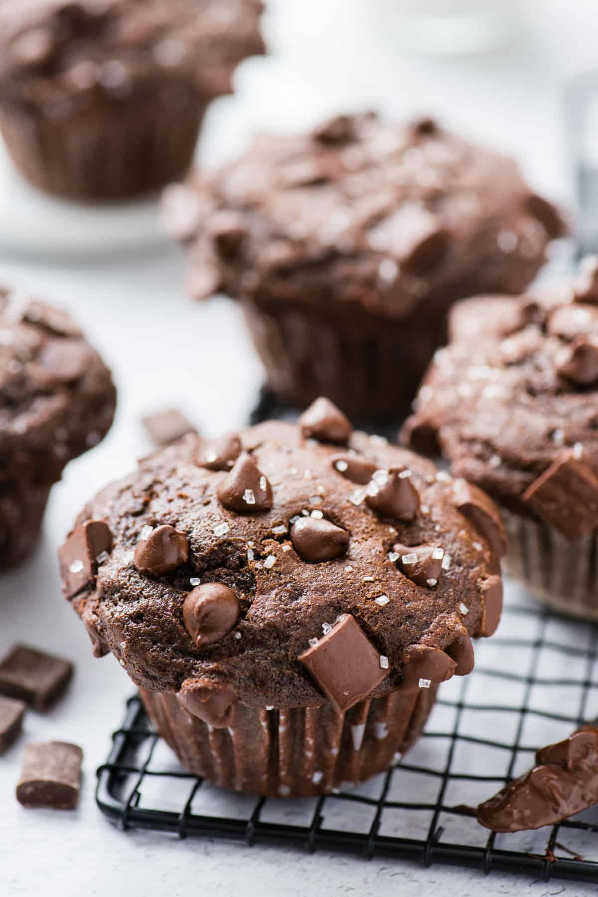 chocolate muffin on black wire rack with more muffins in the background