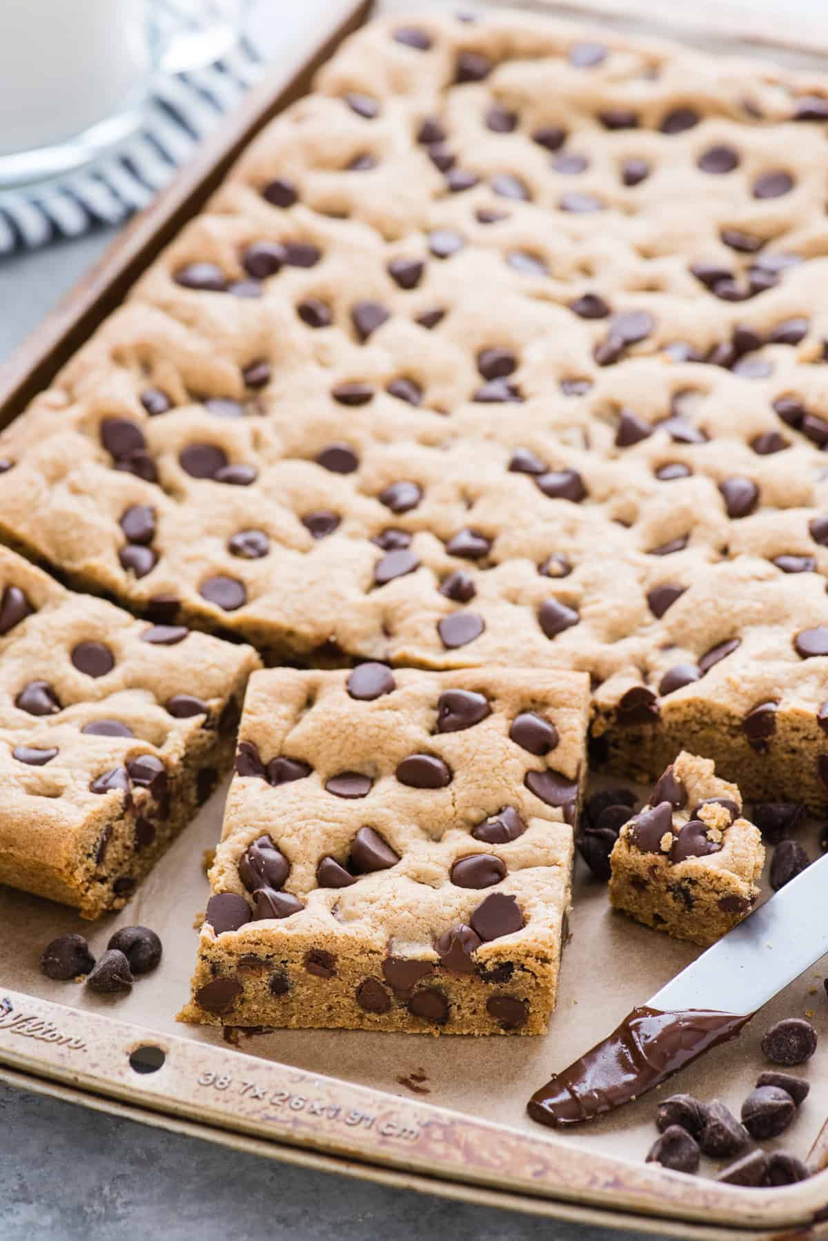 chocolate chip cookie bars in baking sheet with one cookie cut into a square