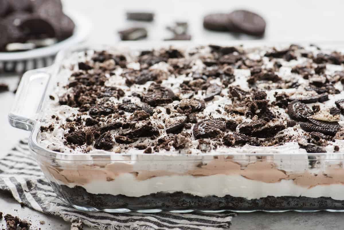 no bake oreo dessert in glass 9x13 inch pan with blue striped napkin under the pan