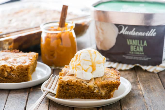 Slice of pumpkin earthquake cake on white plate with scoop of vanilla ice cream on top