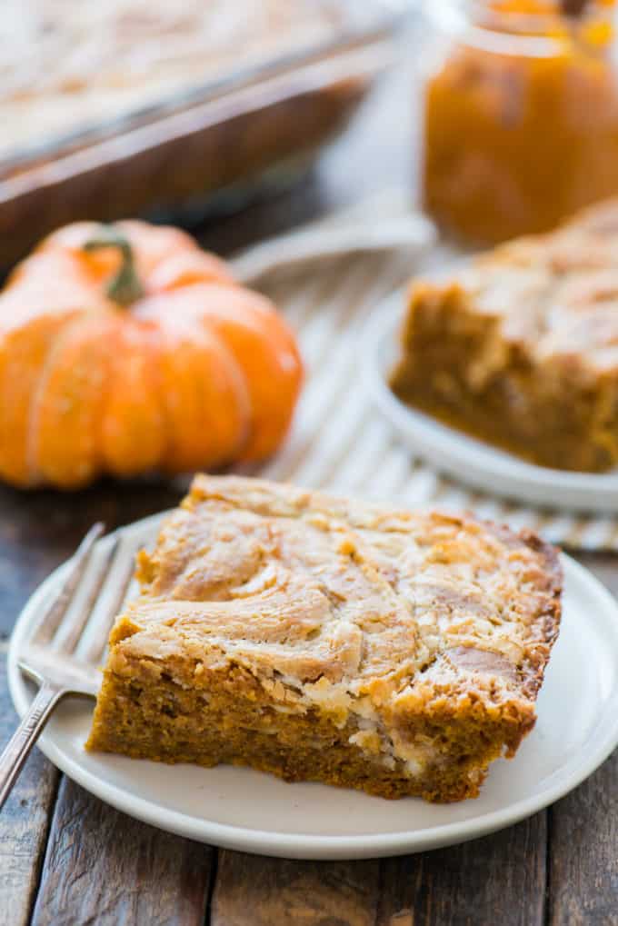 Slice of pumpkin earthquake cake on white plate with pumpkin in background