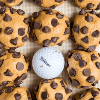 Balls of pumpkin chocolate chip cookie dough with golf ball to demonstrate size