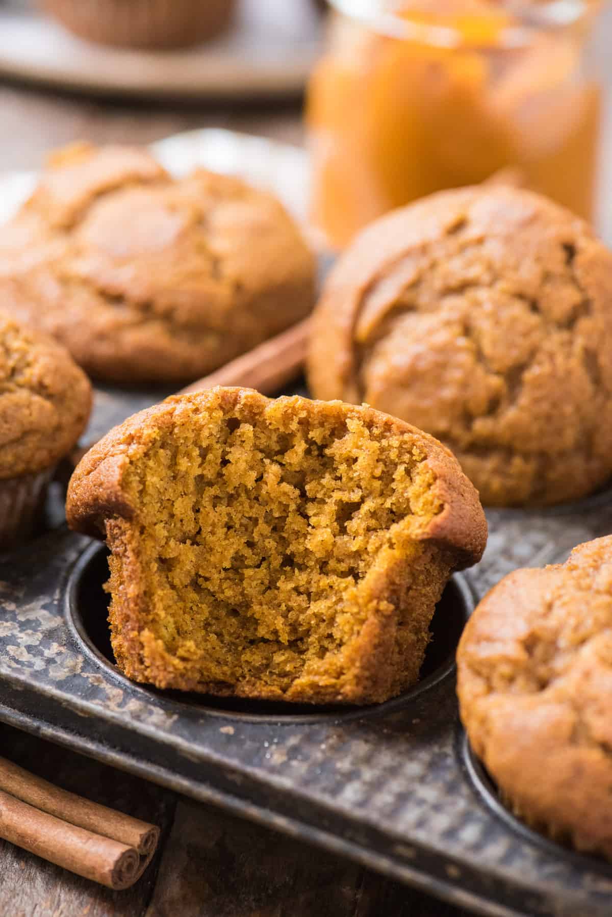 pumpkin muffin with bite taken out arranged in metal muffin pan 
