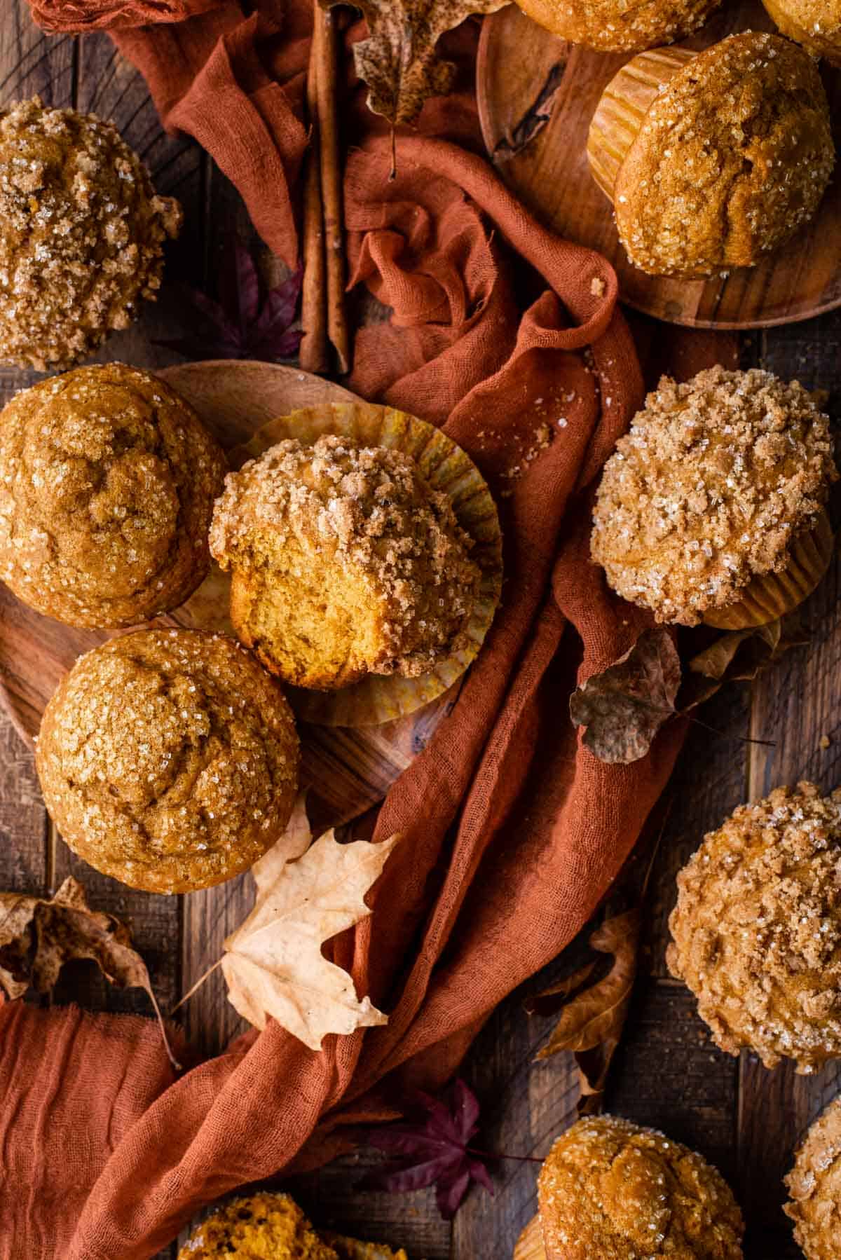 pumpkin muffins arranged on wood background with orange linen and fall leaves