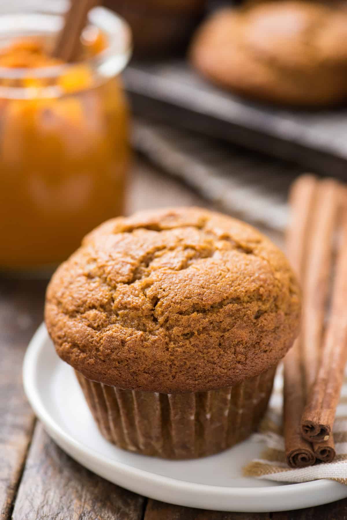 pumpkin muffin on white plate with cinnamon sticks on the right side