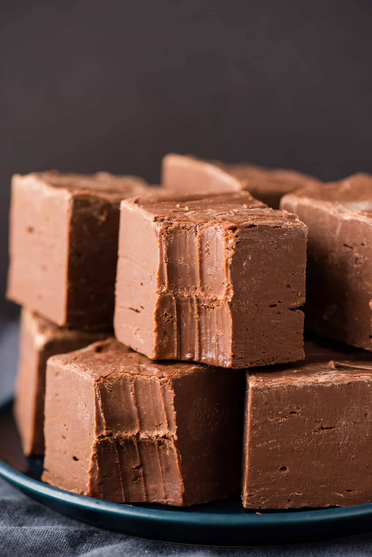 chocolate fudge cut into squares stacked on navy blue with black background