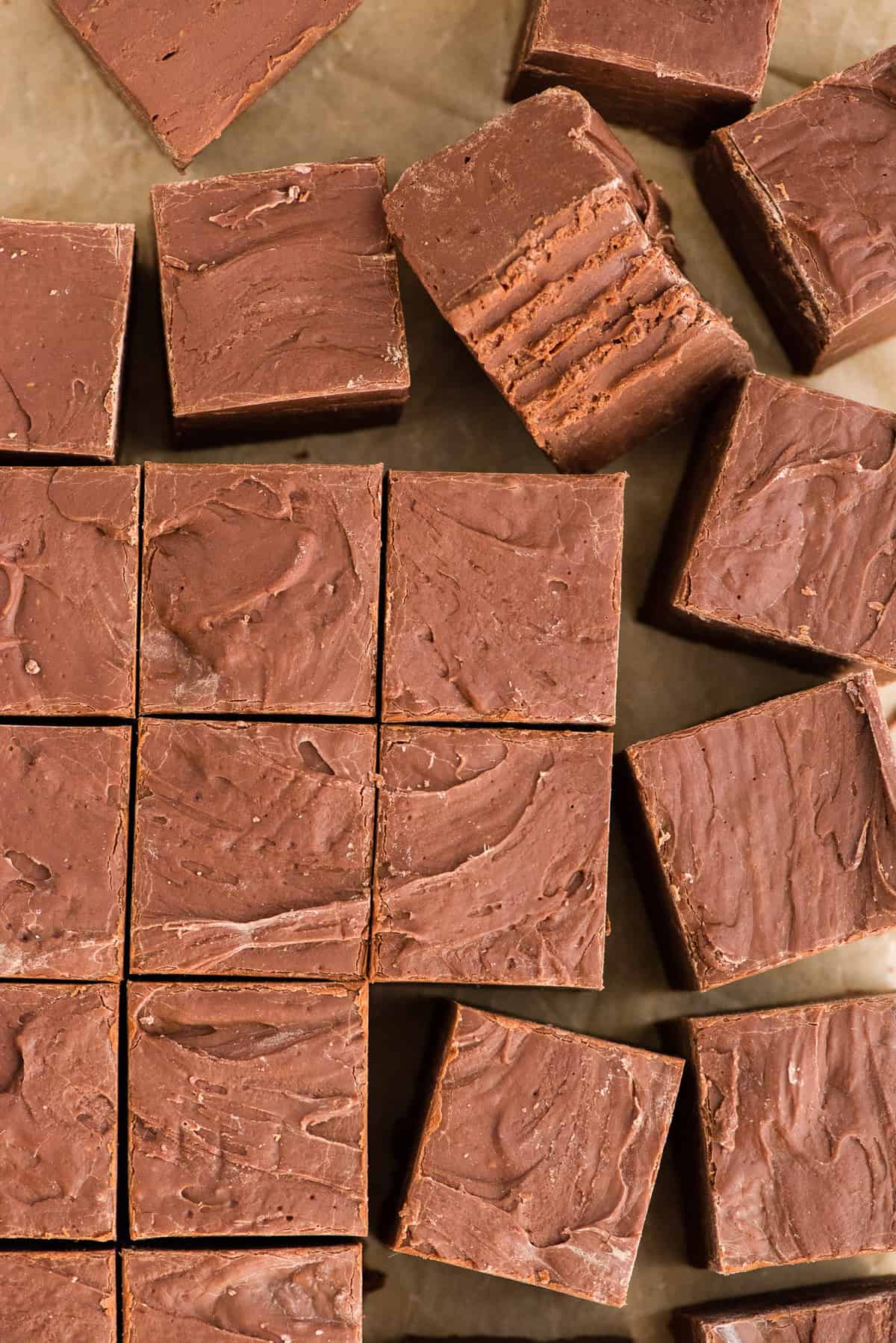 chocolate fudge cut into squares arranged in grid pattern on brown parchment paper