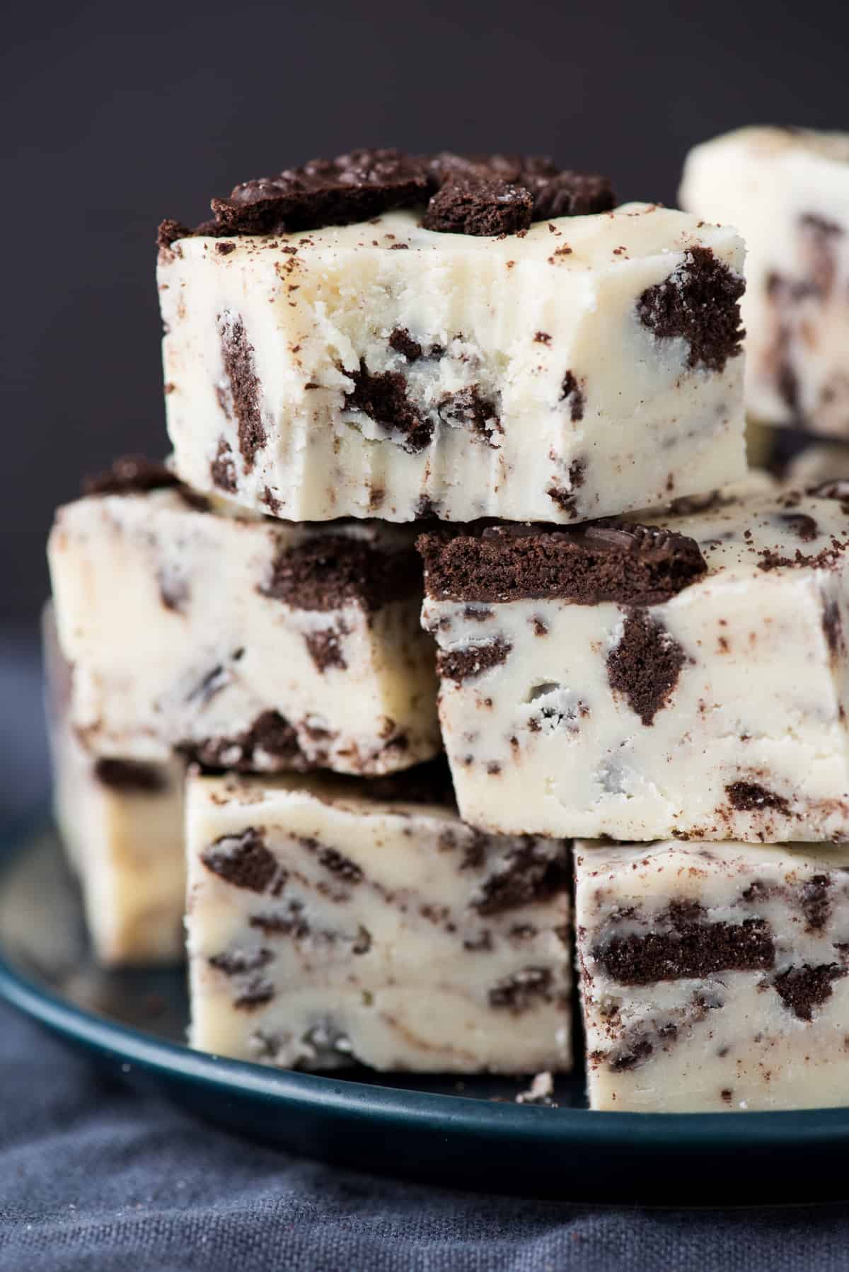 oreo fudge cut into squares and stacked on top of each other on dark background