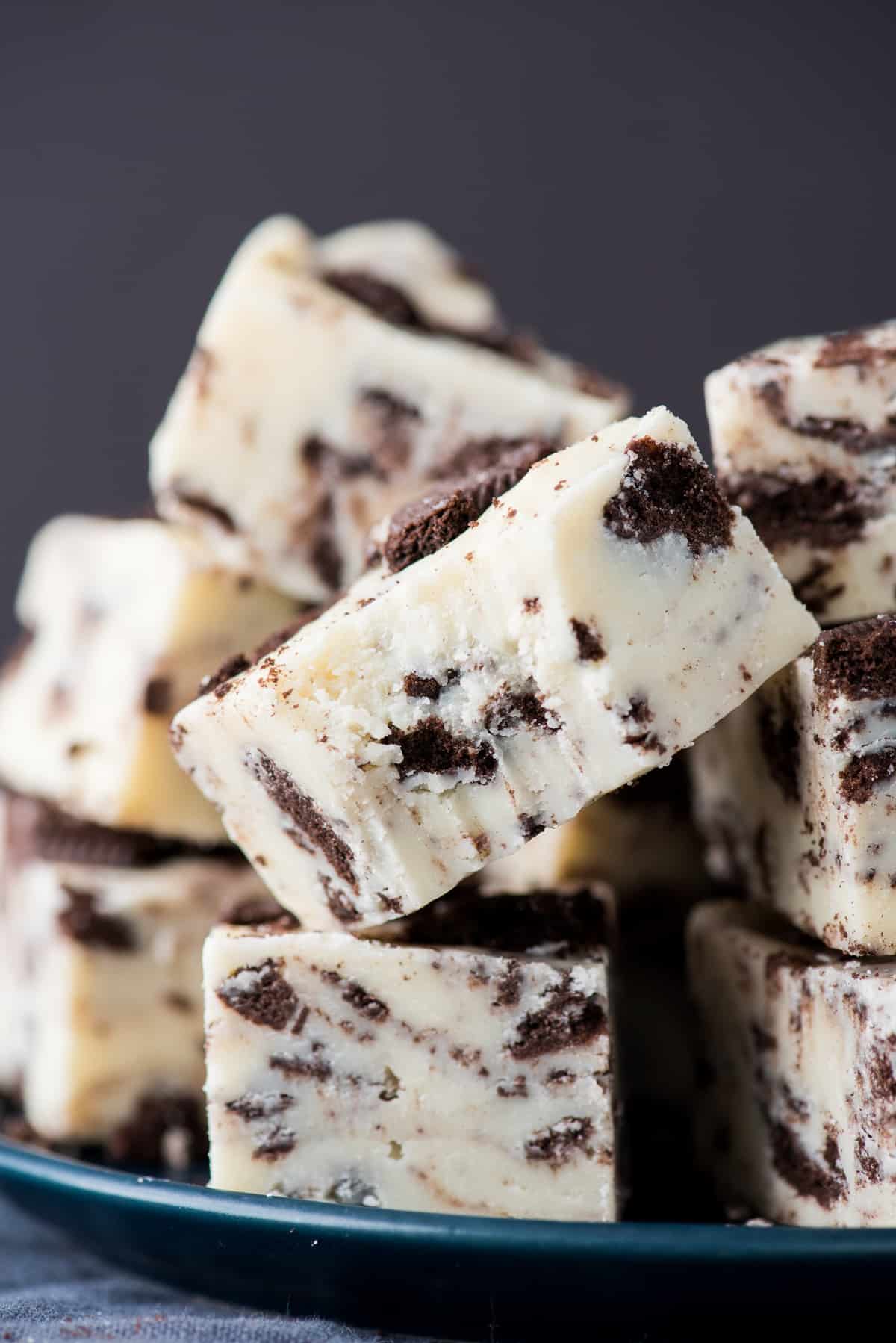 oreo fudge cut into squares and stacked on top of each other on dark background