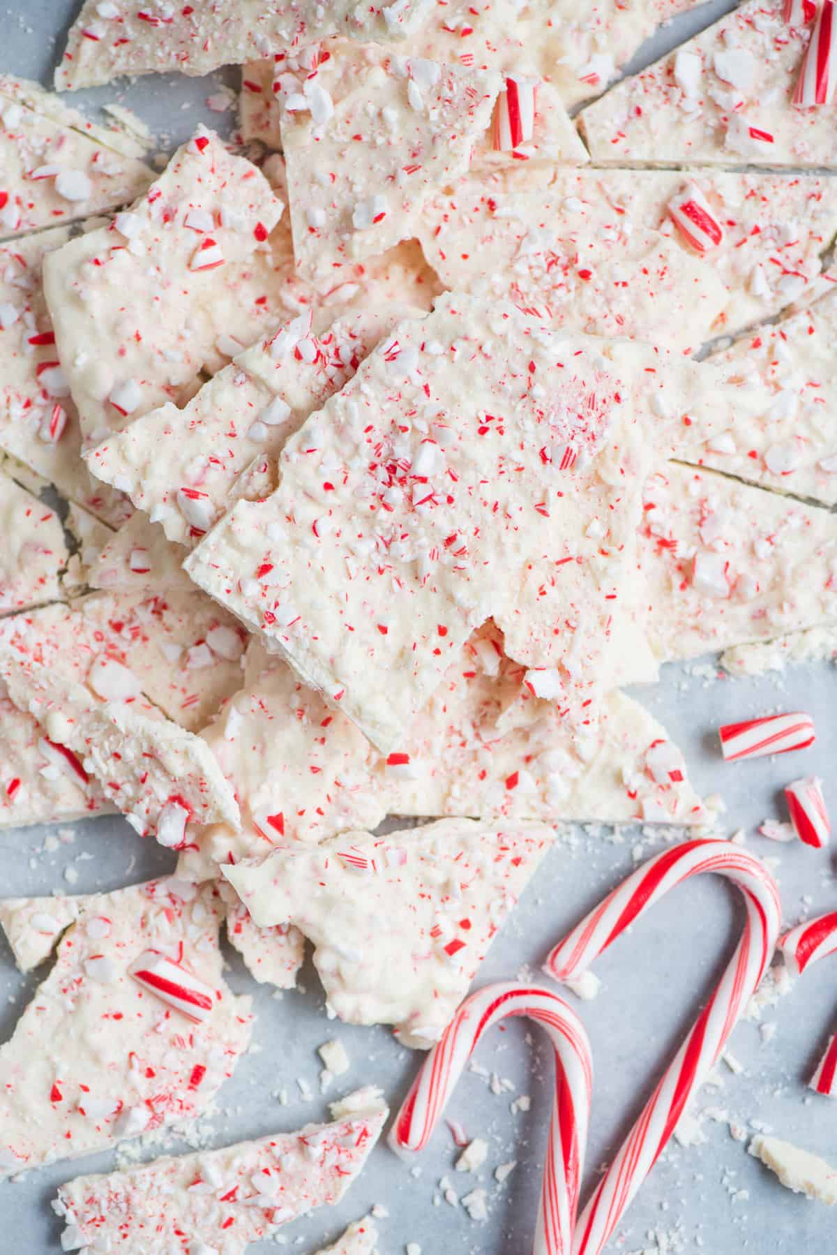 white peppermint bark arranged on gray surface with candy canes