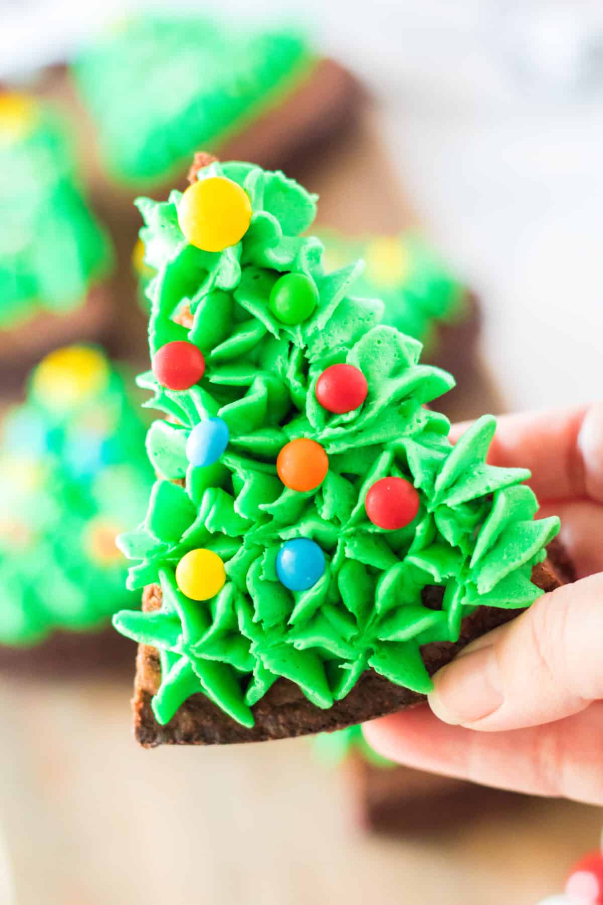 hand holding triangle brownies decorated to look like a Christmas tree