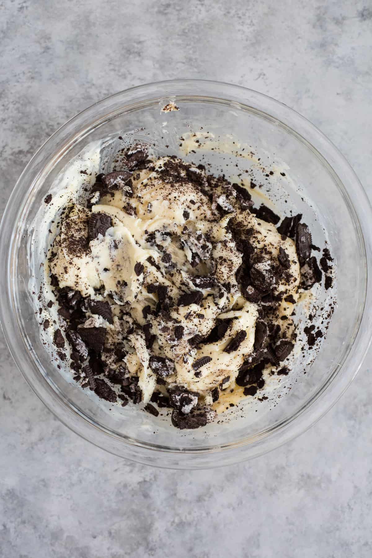 glass bowl with white chocolate chips, sweetened condensed milk, and chopped oreos