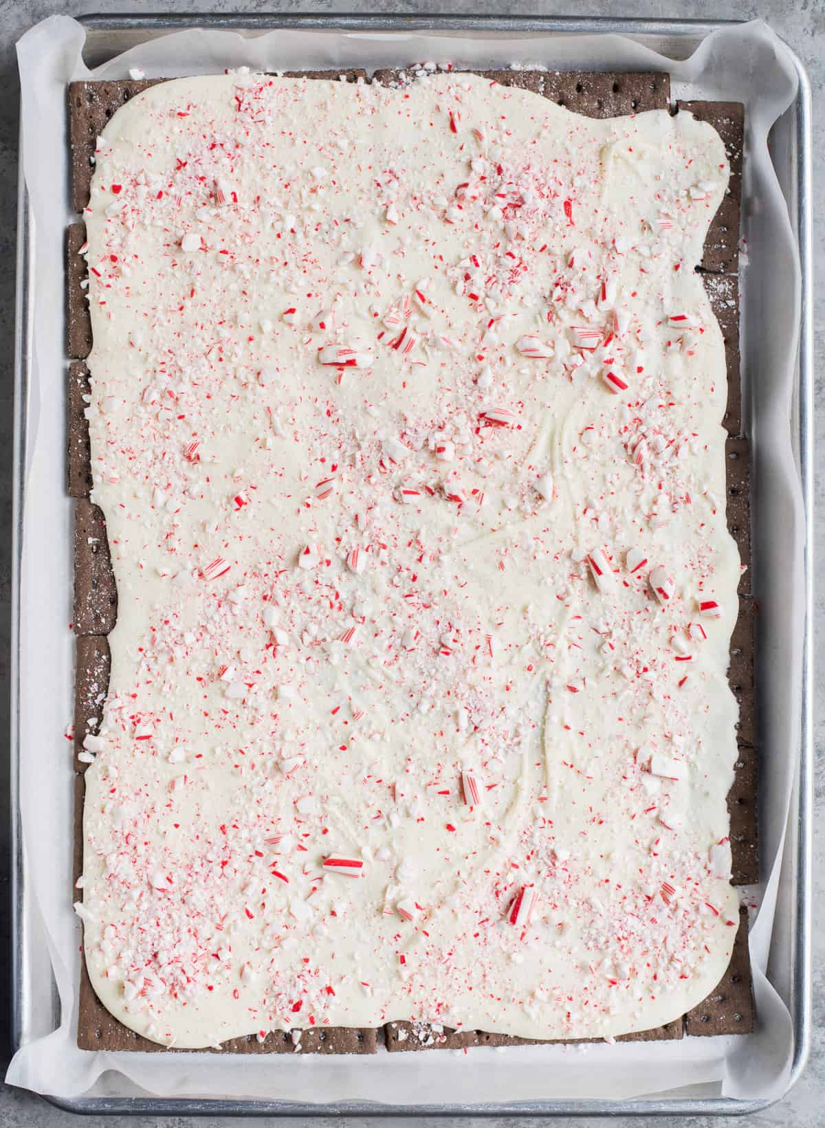 melted white chocolate and crushed candy canes spread over chocolate graham crackers