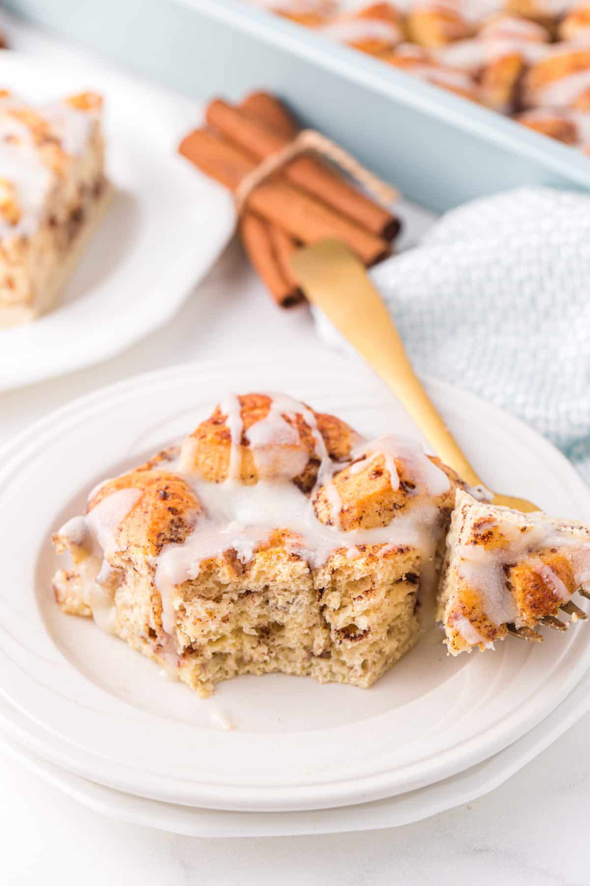 slice of cinnamon roll casserole with icing on white plate