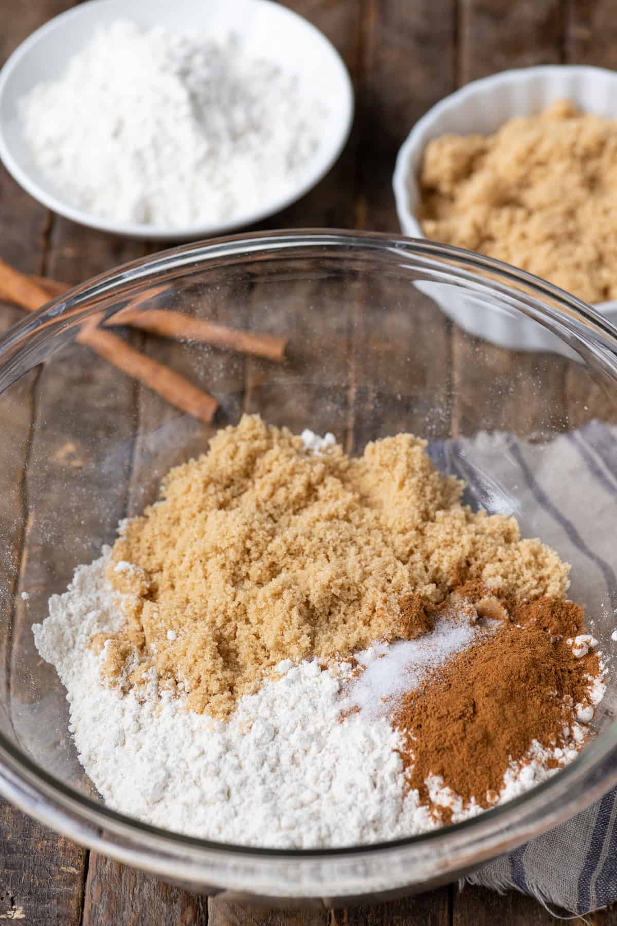 flour, brown sugar and cinnamon in glass bowl on wood background