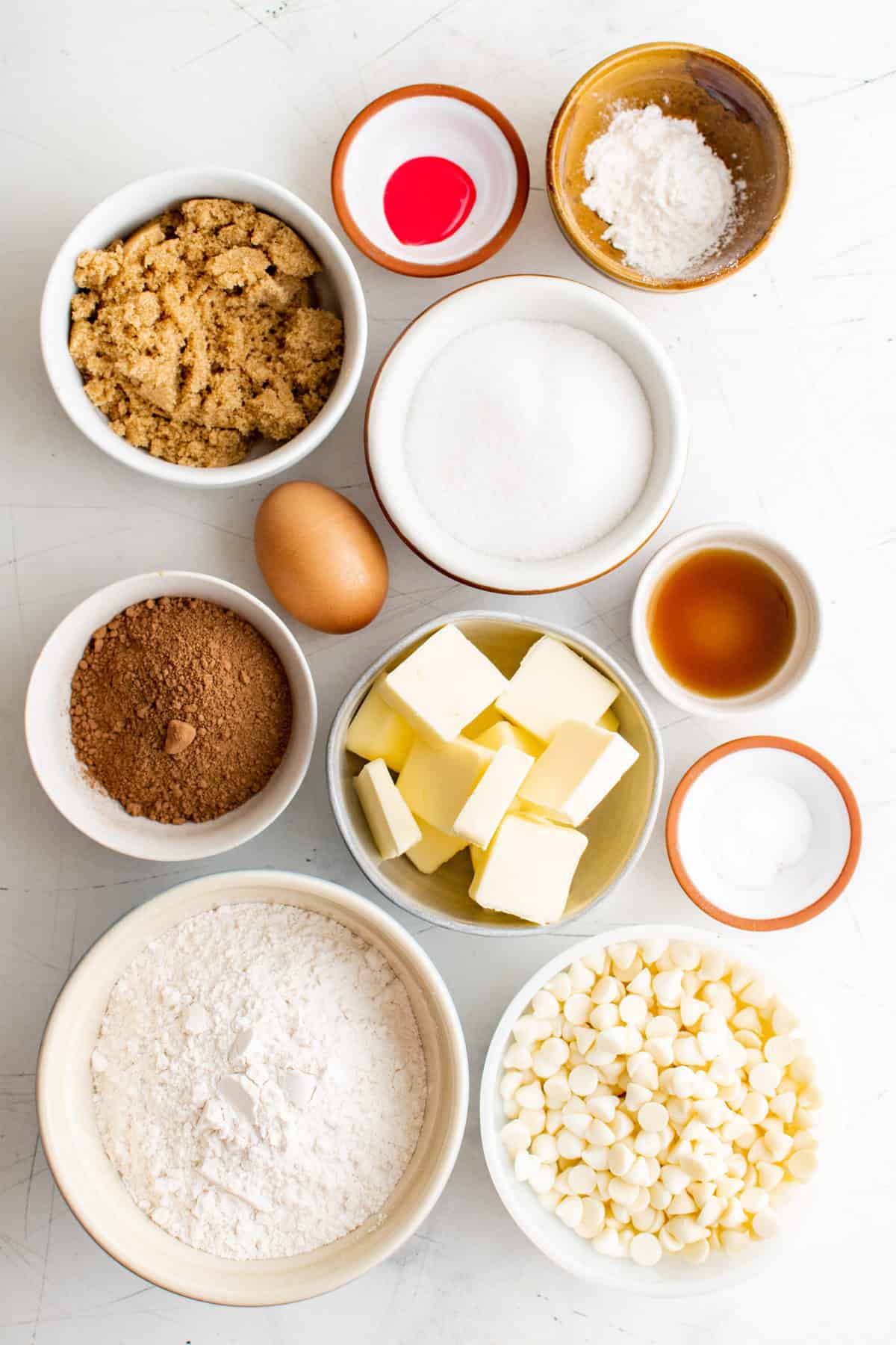 ingredients to make red velvet cookies displayed in bowls on white background