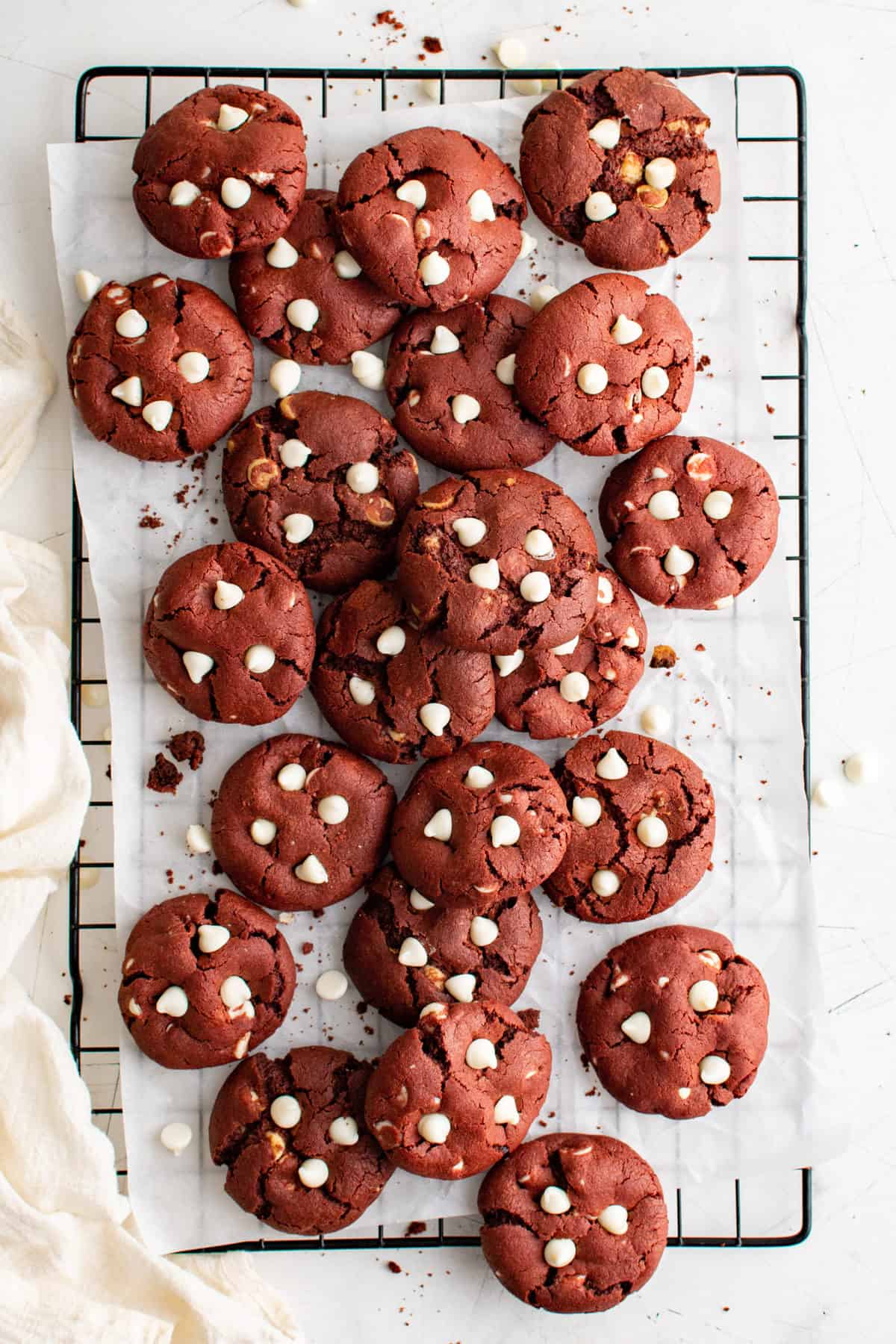 red velvet cookies with white chocolate chips on wire rack on white background