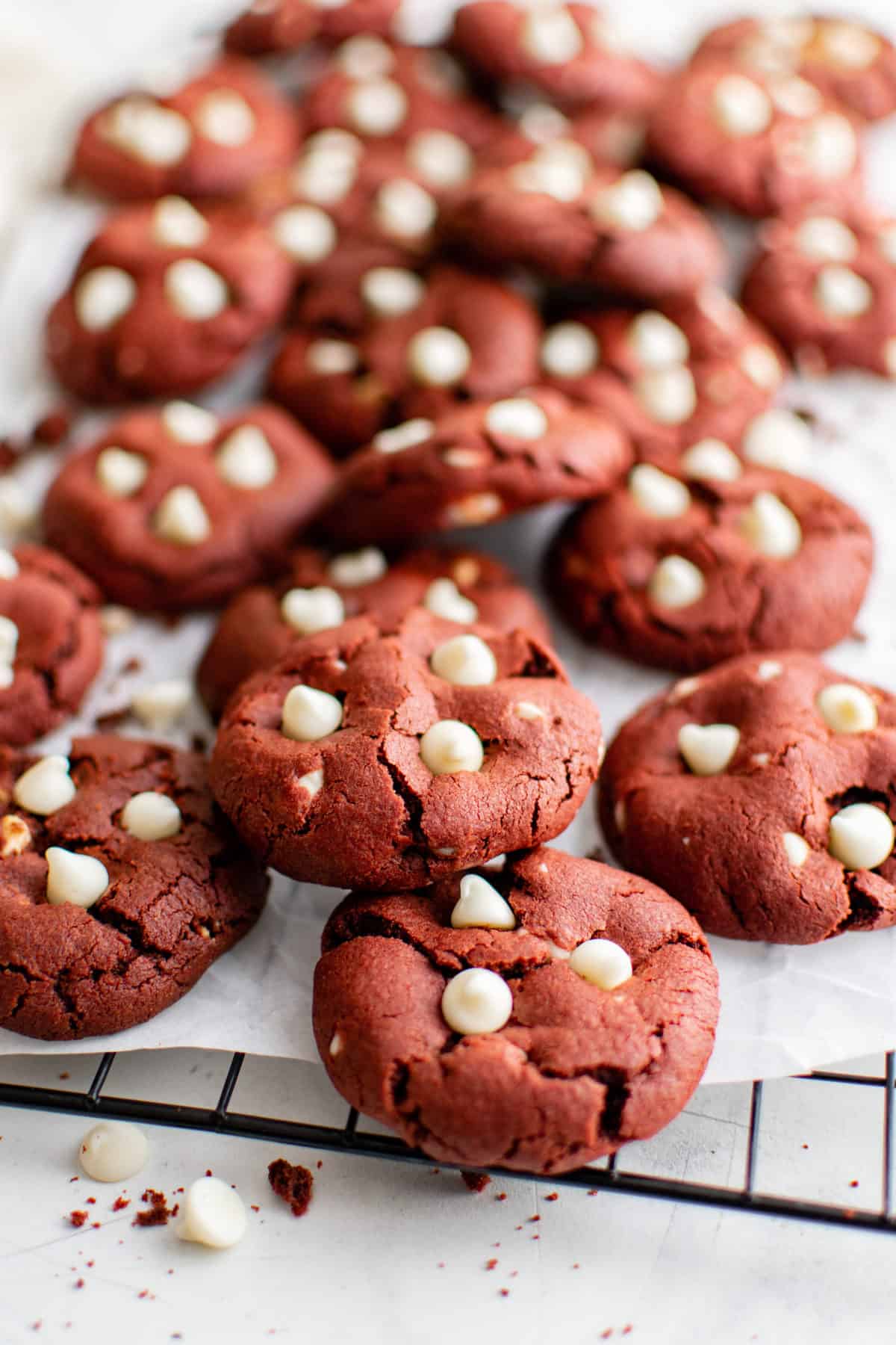 red velvet cookies with white chocolate chips on wire rack on white background