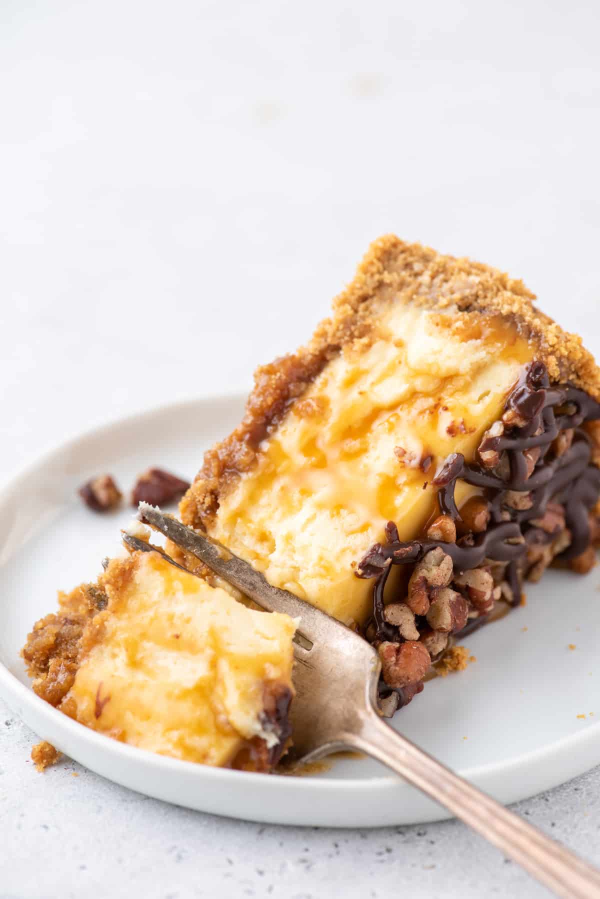 slice of turtle cheesecake on white plate with fork