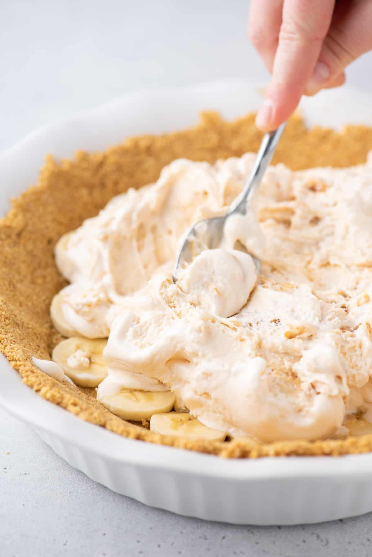 spoon spreading ice cream into pie crust