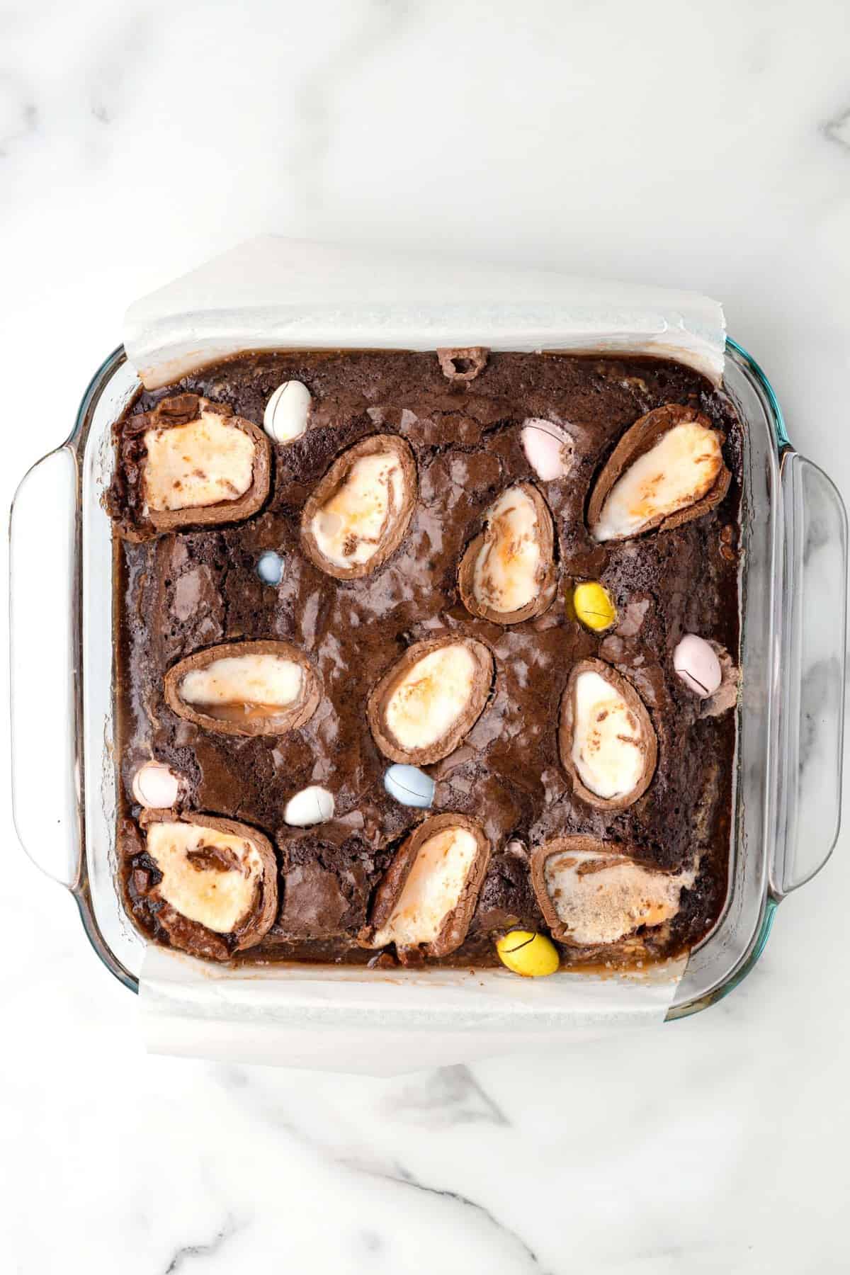 creme egg brownies easter dessert in glass pan on white background