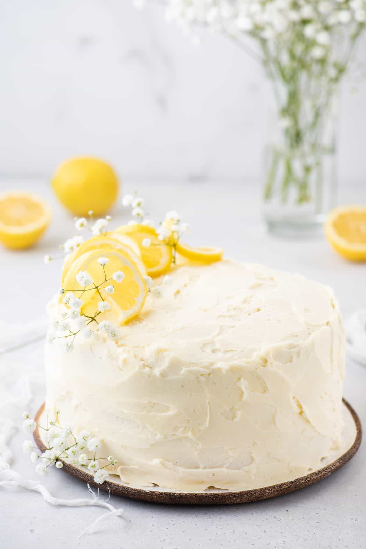 Whole lemon cake on plate, with baby's breath and lemon slices as garnish