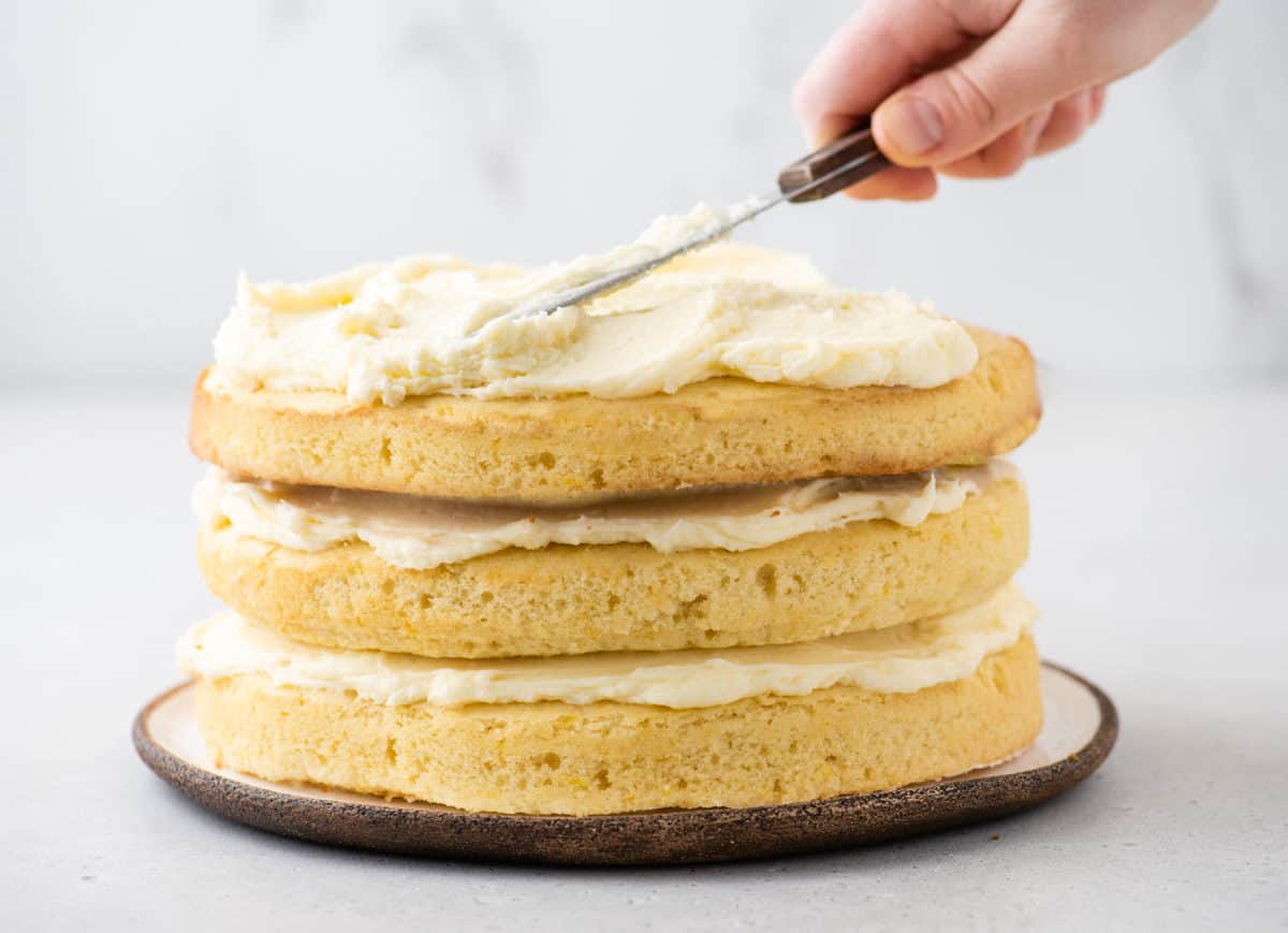 Frosting the top of a three-layer cake using an offset spatula