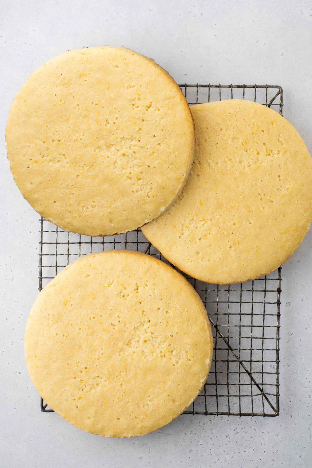 Three round lemon cake layers on wire cooling rack