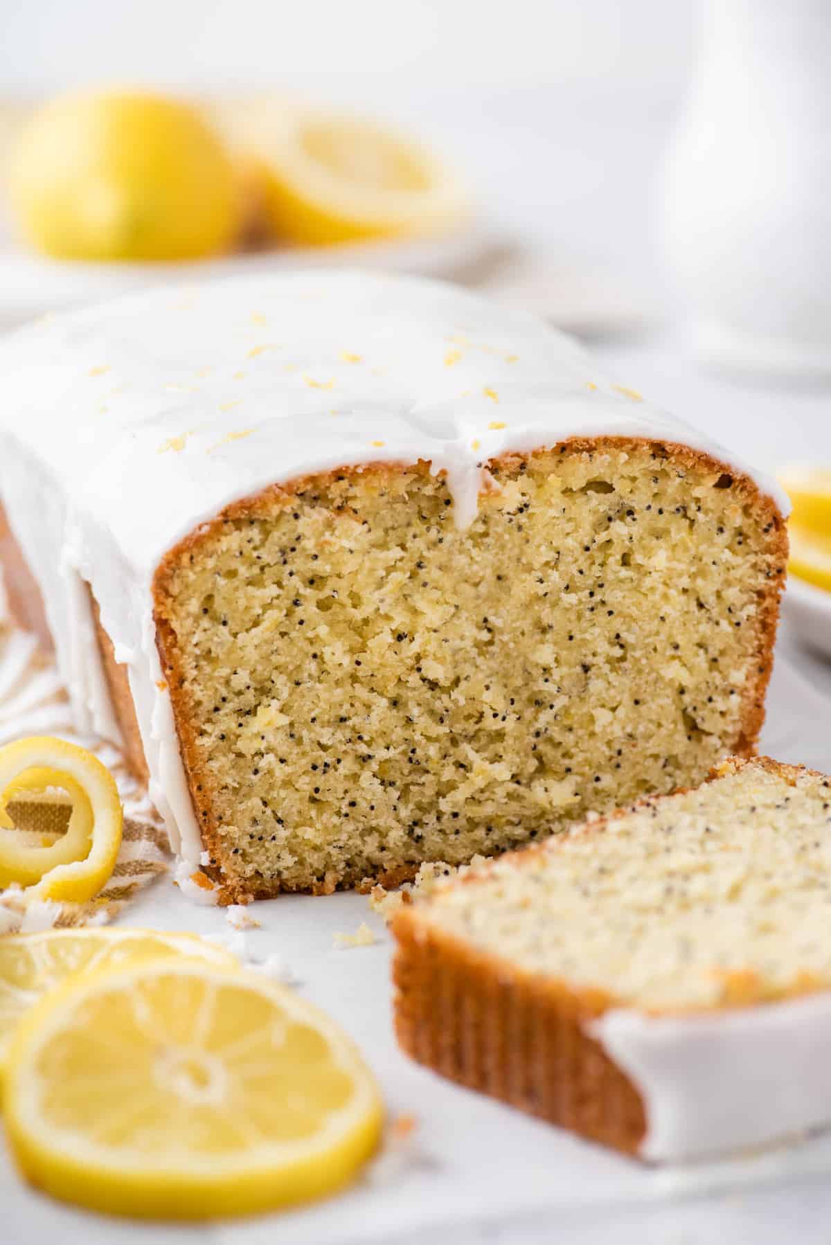 Loaf of lemon poppy seed bread with slice cut to show inside