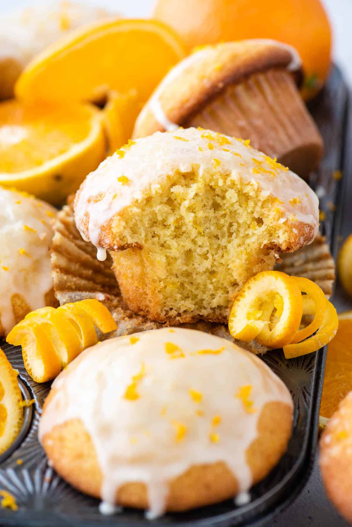 orange muffin with bite removed in muffin pan