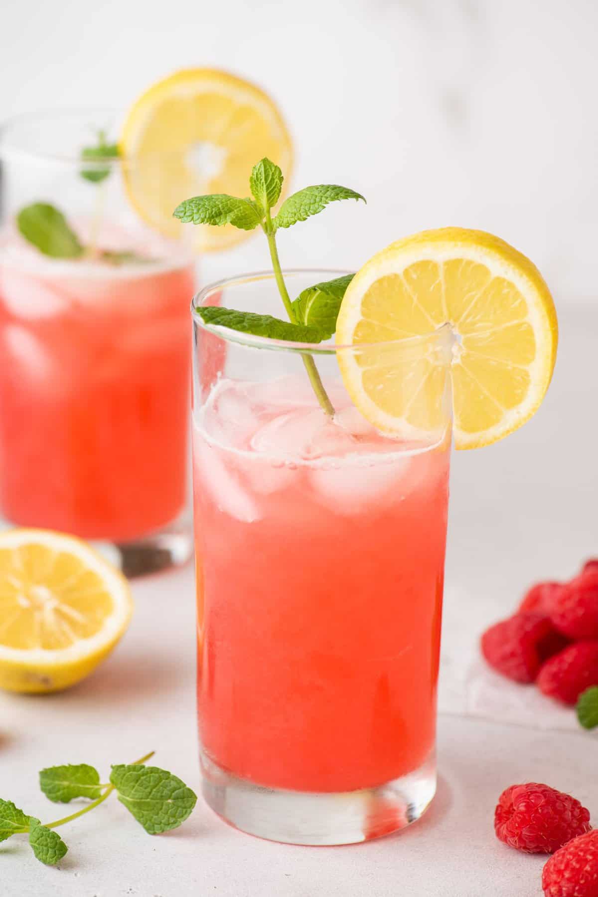 Glass of raspberry lemonade with sprig of mint and slice of lemon