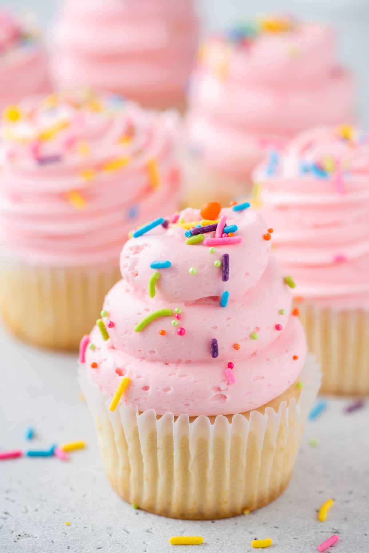 Vanilla gluten-free cupcakes topped with pink frosting and sprinkles