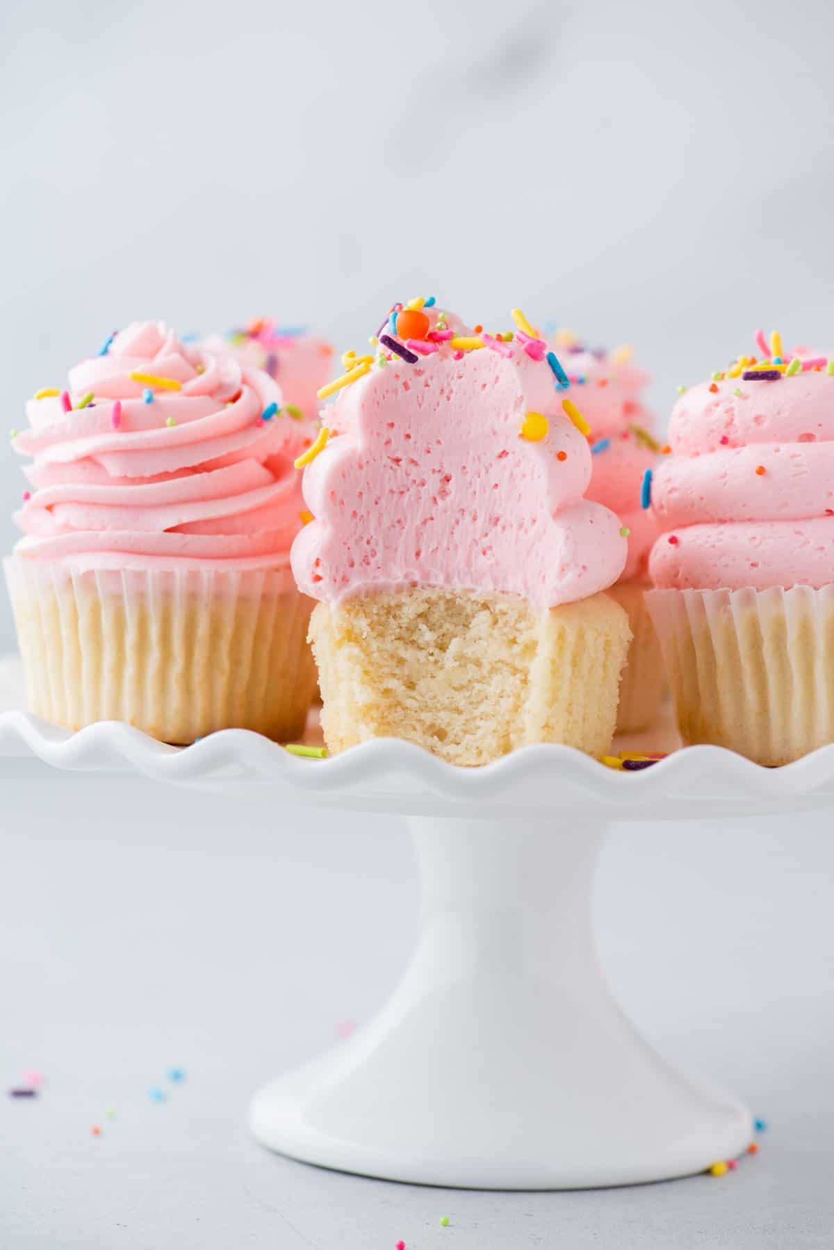 Gluten-free cupcakes on cake stand, with one cut to show light, fluffy cake texture