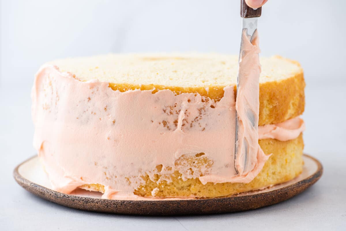 spreading crumb coat on cake with metal spatula