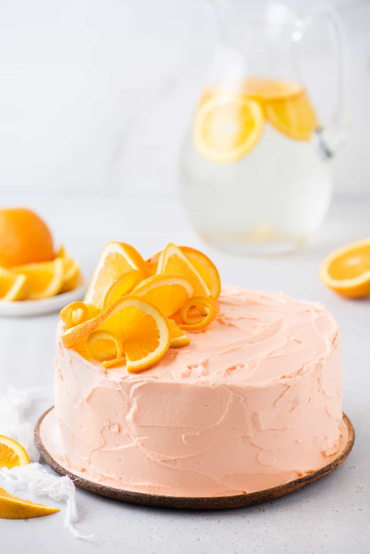 whole orange cake on plate decorated with fresh orange slices with white background