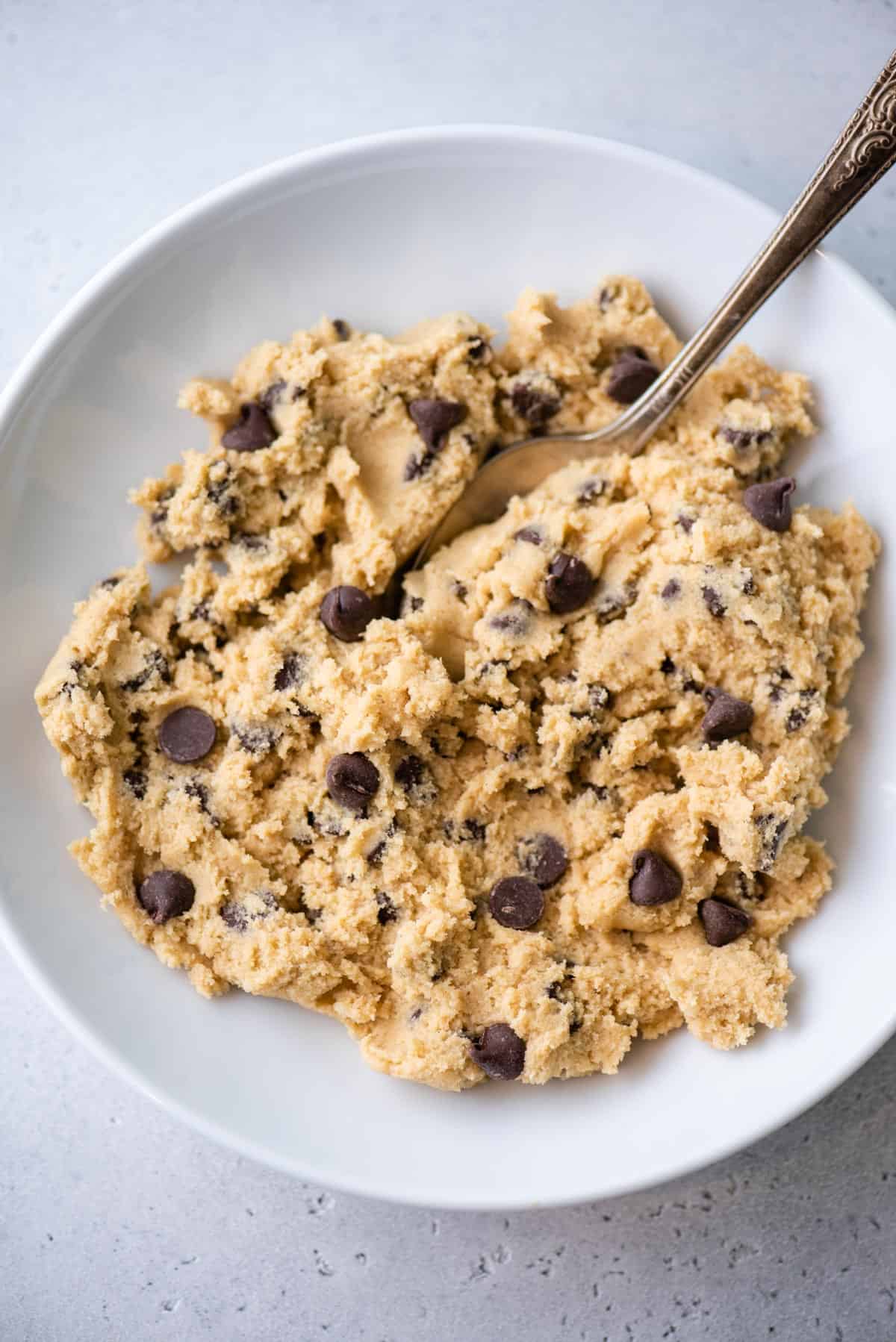 Overhead view of chocolate chip cookie dough in bowl with spoon