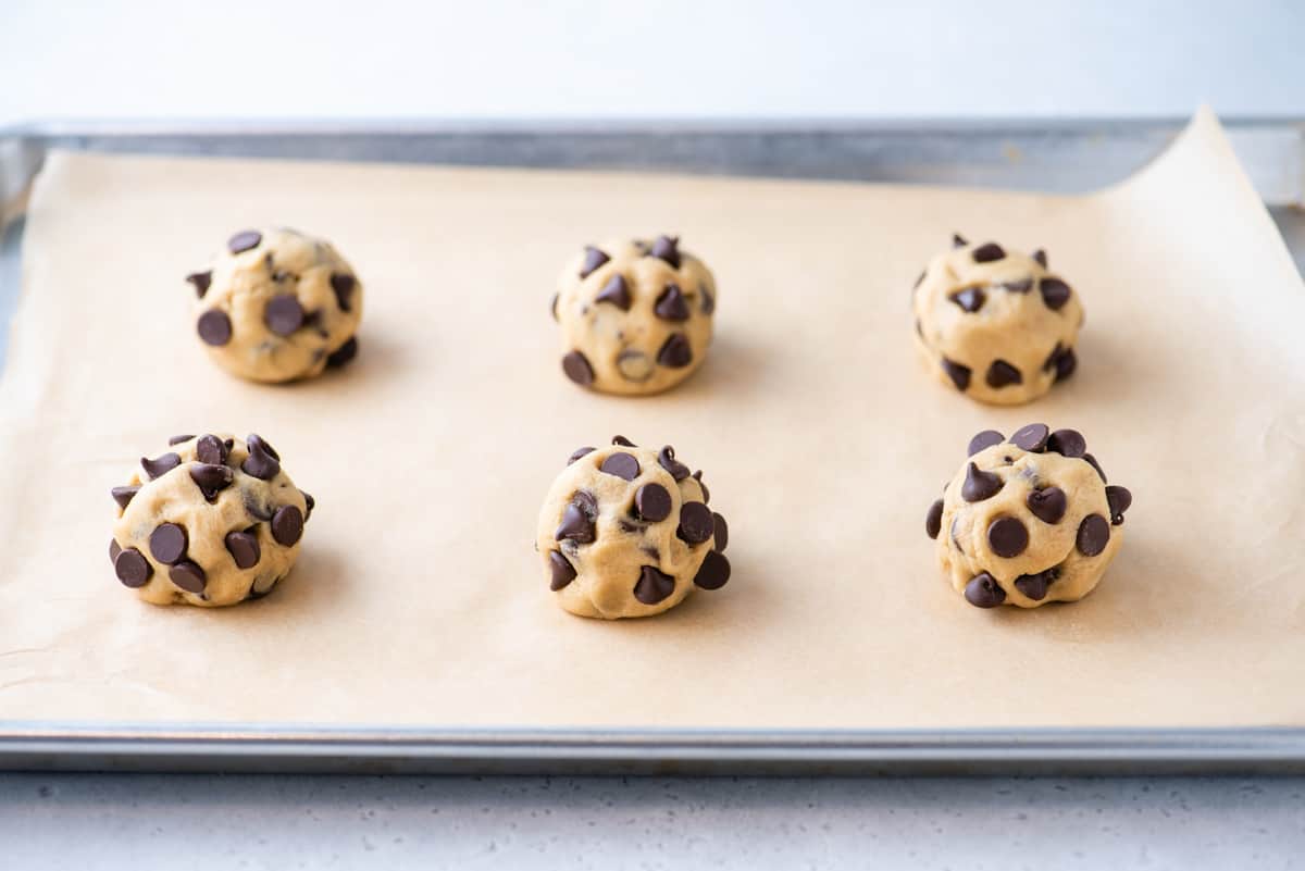 6 balls of cookie dough on parchment-lined baking sheet