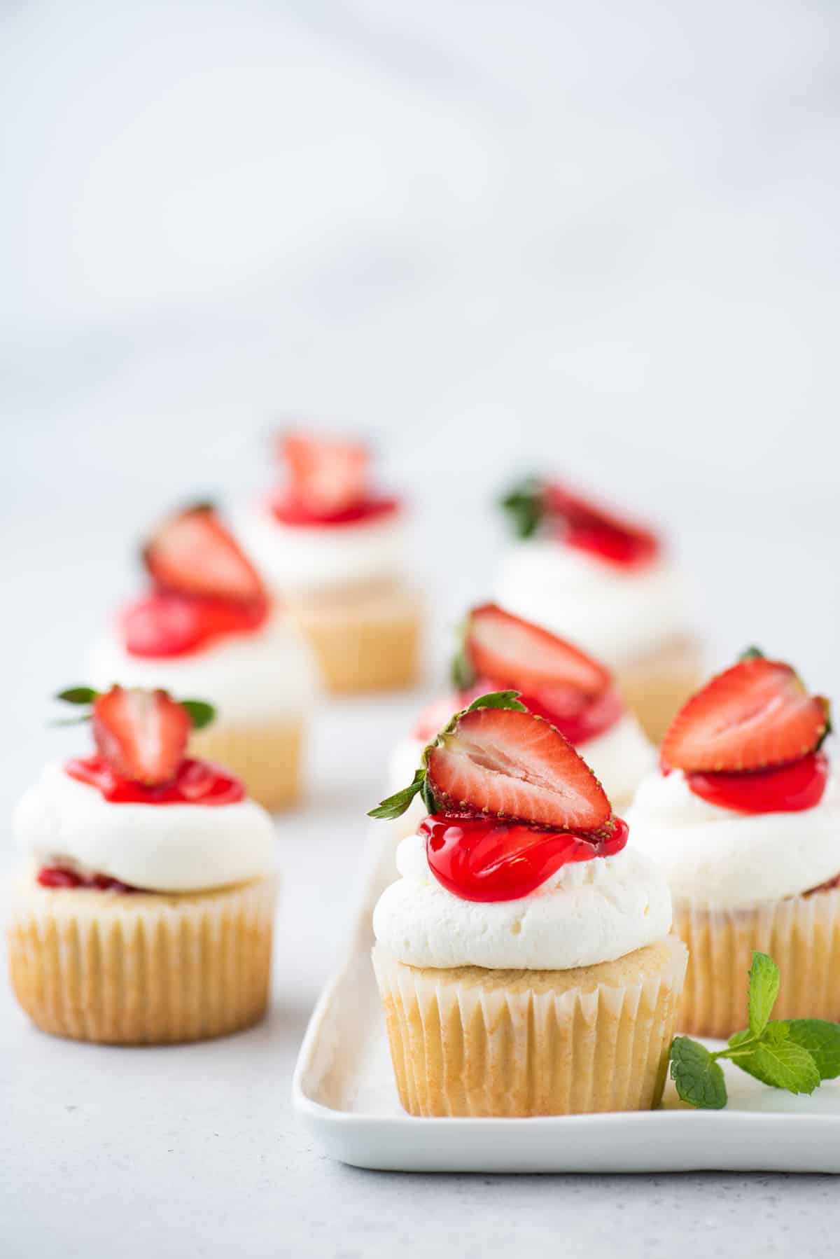 Strawberry shortcake cupcakes on white platter and tabletop